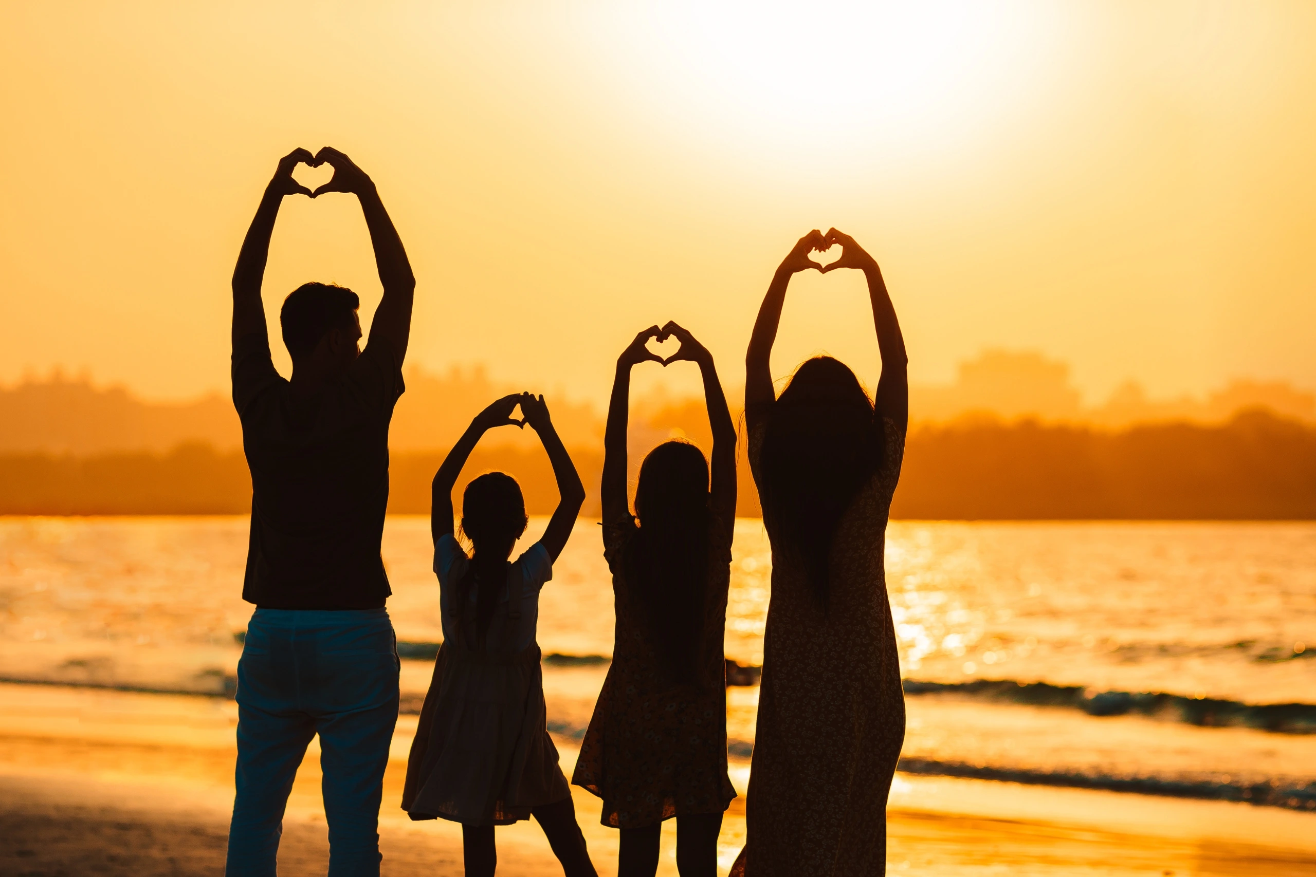 Three people stretching on the beach at sunset