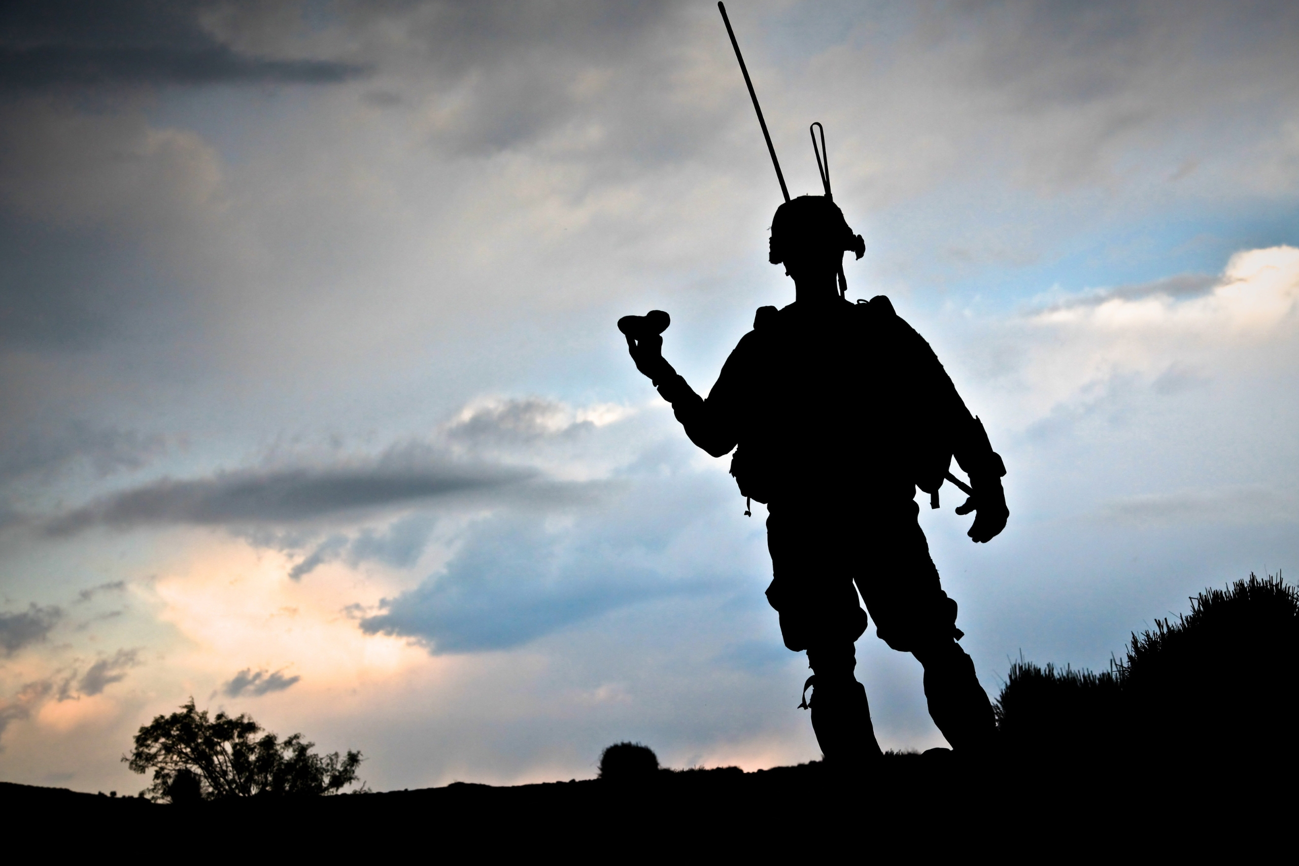 Silhouette of a soldier with a weapon against a sunset sky