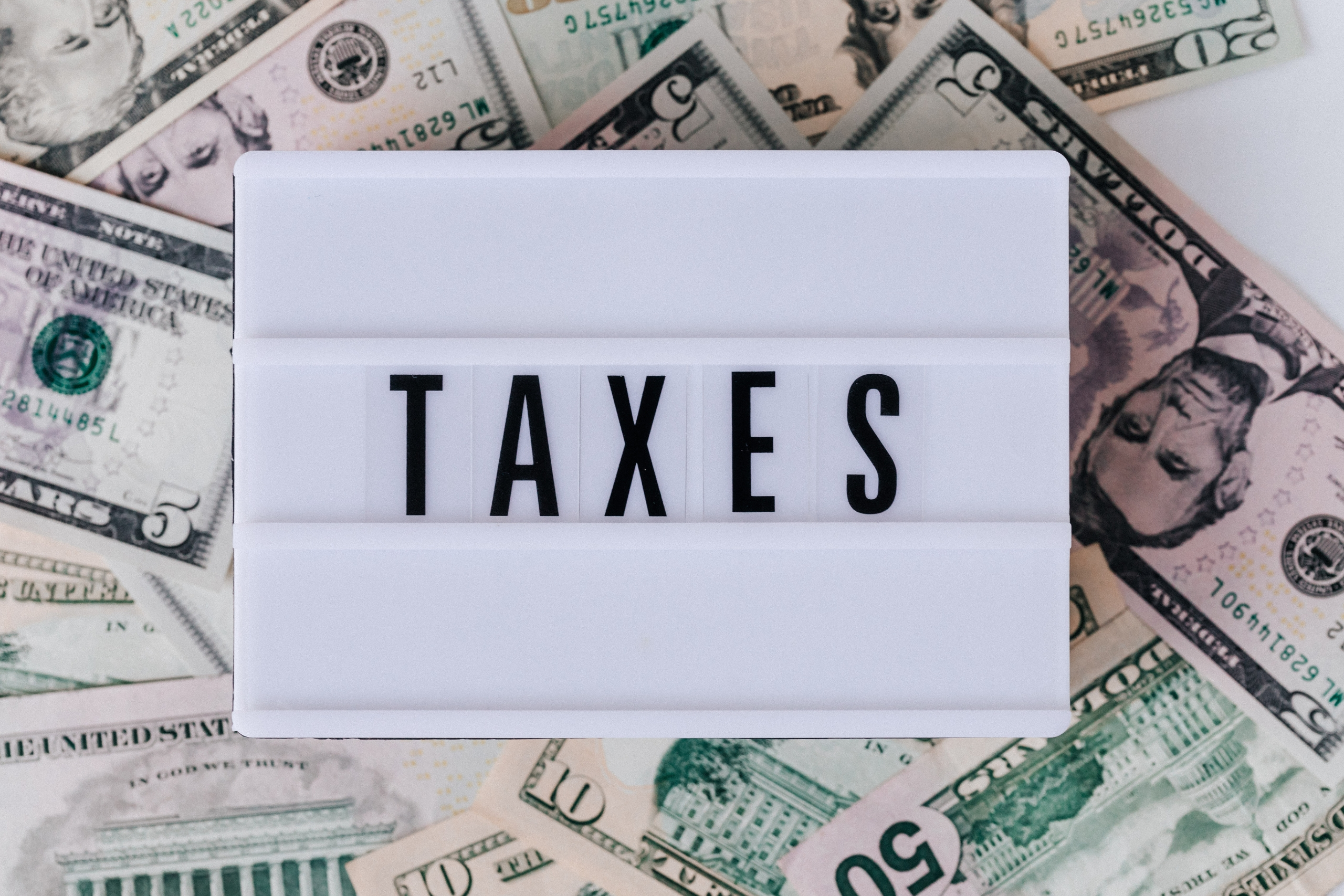 TAXES sign with US dollar bills in the background
