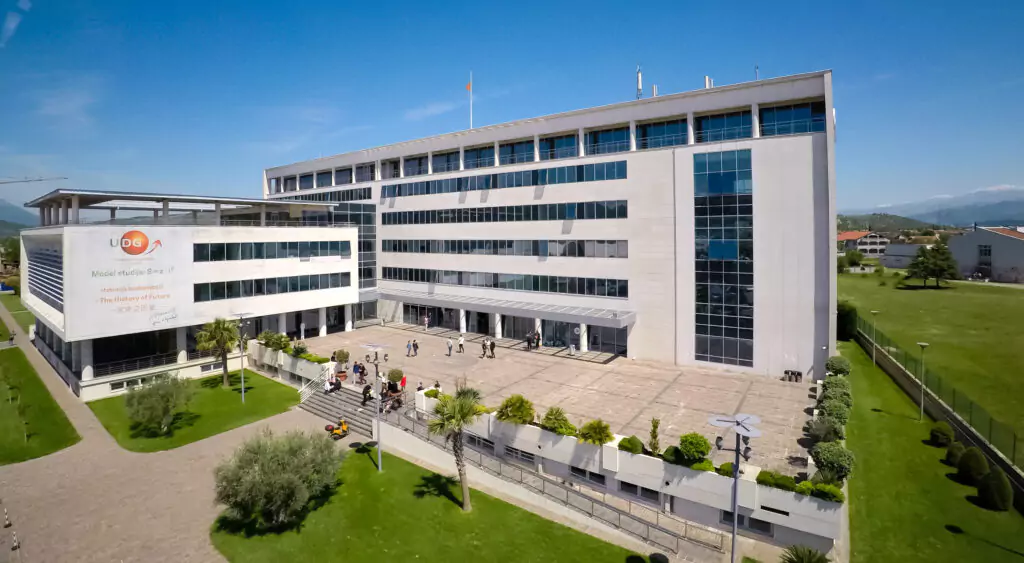 Modern university building with a columned entrance and flags.